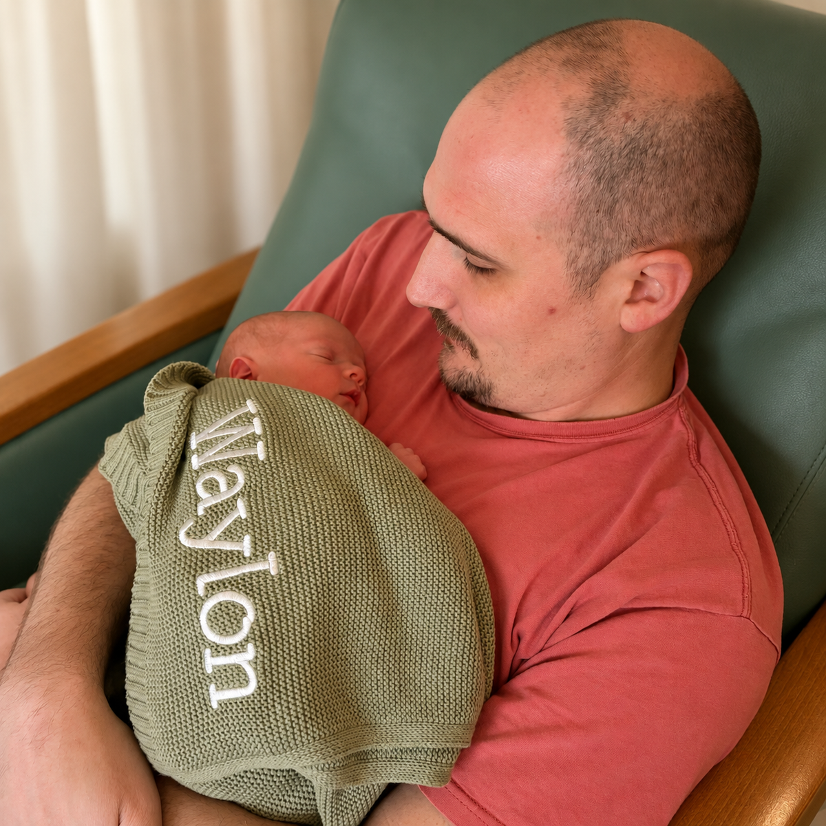 Father holding his newborn wrapped in an olive blanket embroidered Waylon